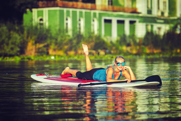 SUP Stand up Surf girl with paddle at sunset