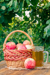 Just picked apples in a wicker basket and apple cider in glass goblet on wooden boards