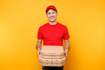 Delivery man in red cap, t-shirt giving food order pizza boxes isolated on yellow background. Male employee pizzaman or courier in uniform holding italian pizza in cardboard flatbox. Service concept.