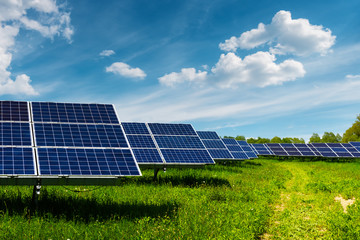 Solar panel on blue sky background. Green grass and cloudy sky. Alternative energy concept