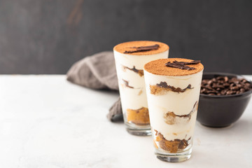 Homemade tiramisu, traditional Italian dessert in glass on white table. Copy space.