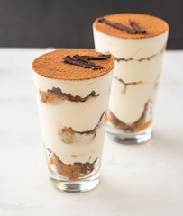 Homemade tiramisu, traditional Italian dessert in glass on white table. Copy space.