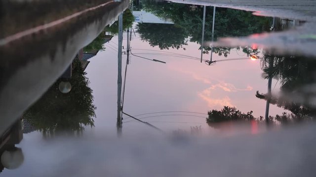 reflection twilight sunset sky in puddle water flooding on street