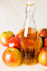 Bottle of fresh apple cider near autumn apples