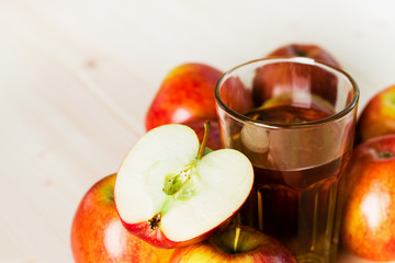 Glass of fresh apple cider and half apple near autumn apples.