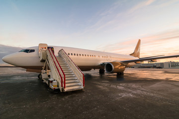 Passenger airplane parked at the airport. Commercial jet plane with sunset sky background, standing...