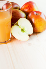 Glass of fresh apple juice and half apple near autumn apples.