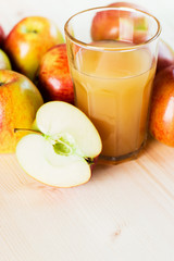 Glass of fresh apple juice and half apple near autumn apples.