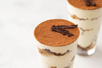 Tiramisu in a glass with coffee beans on white background. Copy space.