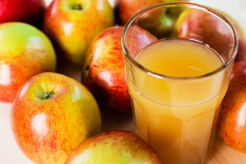 Glass of fresh apple cider near autumn apples