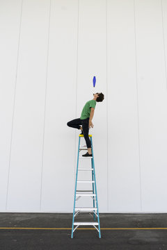 Acrobat standing on ladder, juggling