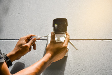 Technician installing IP wireless camera by Hexagon screwdriver on wall  