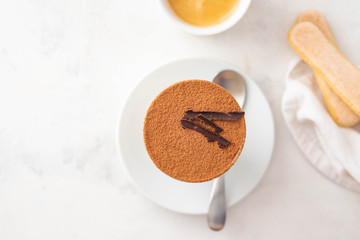 Tiramisu in a glass with coffee beans on white background. Copy space. Top view.