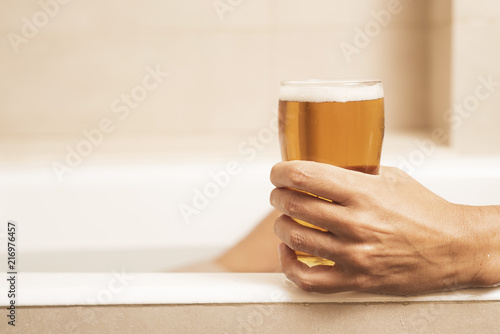 Young Man Drinking A Beer On The Bathtub Stock Photo And