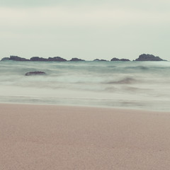 fine art ocean waves and rocks landscape in pastel tones. vintage colors. beach, waves and sky in same tones for artistic outdoor conceptual image