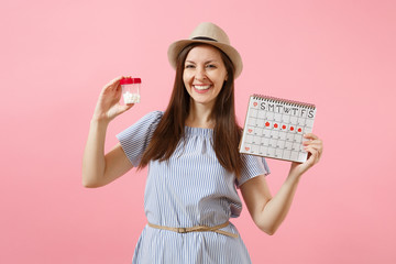 Portrait of young woman in blue dress holding bottle with white pills, female periods calendar, checking menstruation days isolated on background. Medical healthcare gynecological concept. Copy space.