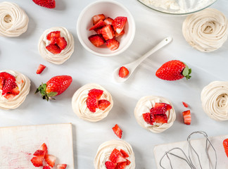 Strawberry pavlova cake nests, meringue decoration on a culinary table