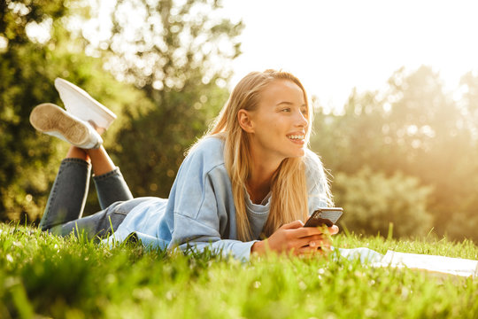 Portrait of a smiling young girl laying on a grass at the park