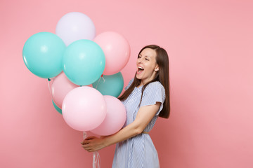 Portrait of fascinating joyful young happy woman wearing blue dress holding colorful air balloons isolated on bright trending pink background. Birthday holiday party, people sincere emotions concept.