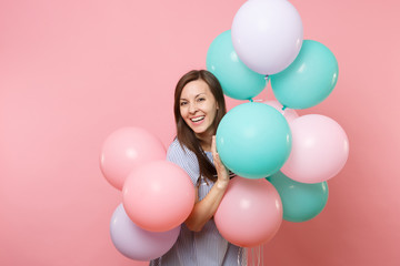 Fototapeta na wymiar Portrait of beautiful smiling young happy woman wearing blue dress holding colorful air balloons isolated on bright trending pink background. Birthday holiday party, people sincere emotions concept.