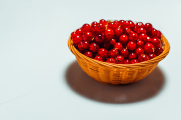 Close up little basket with red currant on white background