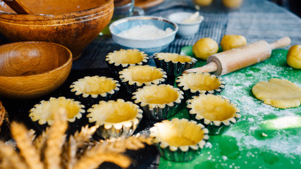 Still life in country style. Tartlets in baking dishes before bake and clay bowl and kitchenware.