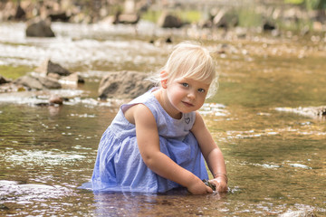 Little girl is playing with water in a river.