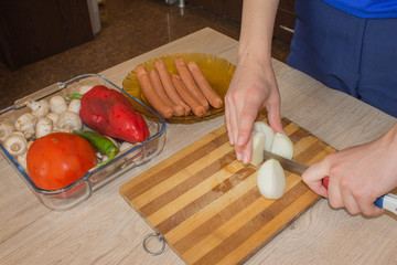 Hands cuts onion with knife. Cooking process concept. Chef prepares meal