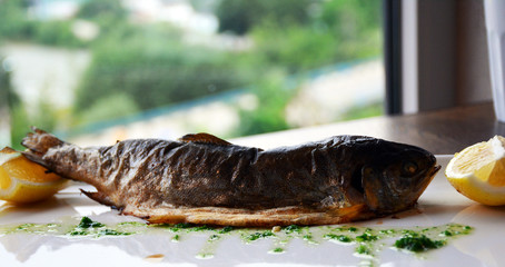Baked trout with lemon on a white plate