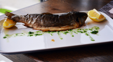 Baked trout with lemon on a white plate
