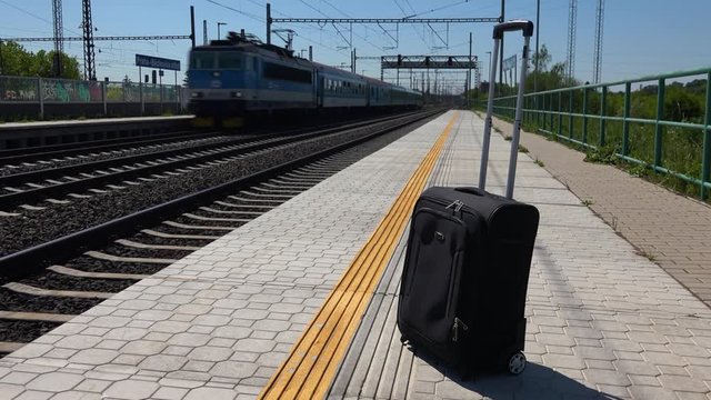 A lone suitcase on a train station platform on a sunny day