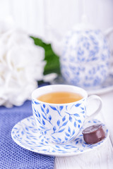 Elegant cup of green tea, candy and white hydrangea on a light background. Free space
