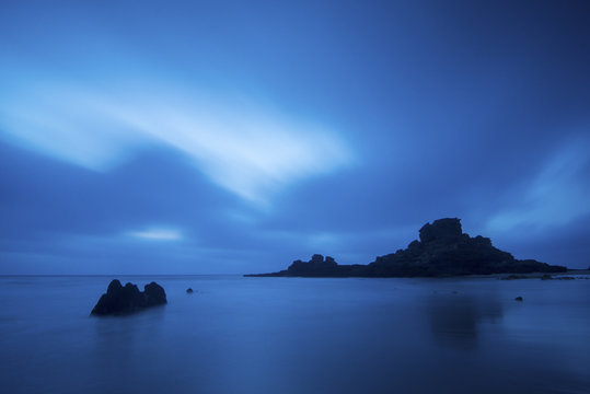 amazing ocean landscape. night time and water lige clouds and fog. rocks in the middle of the sea. long exposure with clouds in movement