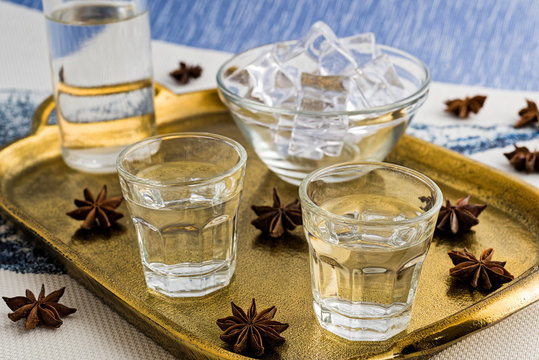 Glasses and bottle of traditional drink Ouzo or Raki on bronze dish with anise star seeds
