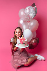 girl with a cake for a birthday, in the Studio on a pink background, festive mood, in full growth, in the hands of a designer cake