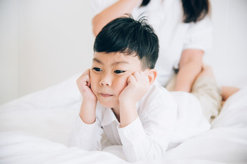Happy loving family. Mother and her son playing on the bed in bedroom.