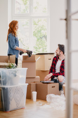Woman and man packing stuff into carton boxes while moving out from the home