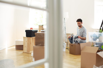 Man unpacking stuff from boxes while furnishing new flat after relocation