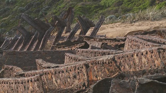 Corroded skeleton of an old, stranded ship wreck in the sunlight on a sandy beach