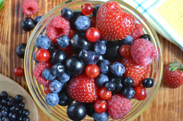 berries of red-blue color on a dark brown wooden background healthy food