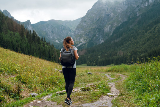 Rear shot of young brunette backpacker woman hiking on the green pathway in Tatra Mountains to Rysy peak . Poland, Slovakia