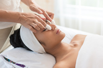 Young asian woman enjoying face massage in luxurious beauty salon.