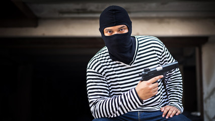 thief or murder hold pistol gun and look at the target for the money at dangerous area in a concept of life, thief, money, safe