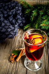 Classic winter autumn hot drink, mulled wine cocktail with  spices, with plaid and Christmas tree branches, on a wooden background, copy space for text