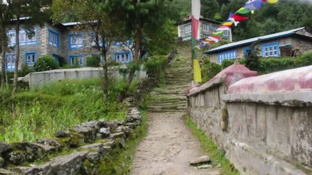A small mountain village in Nepal. Bright blue paint on windows and prayer flags flying.