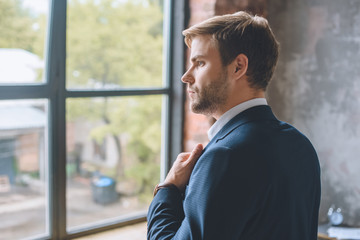 selective focus of young businessman putting on jacket at home