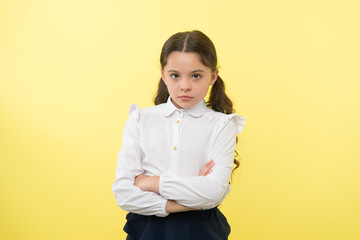 confident schoolgirl. confident and carefree schoolgirl. small schoolgirl with confident look. confident schoolgirl on yellow background.