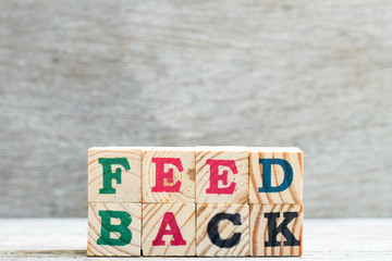 Letter block in word feedback on wood background