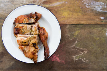 Top view of grilled chicken in white plate on wood background with copy space
