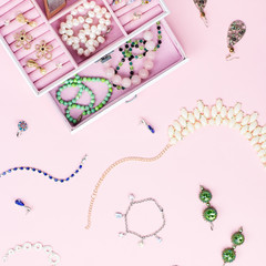 Open jewelry box with neclaces, earrings and rings on pastel background. Top view